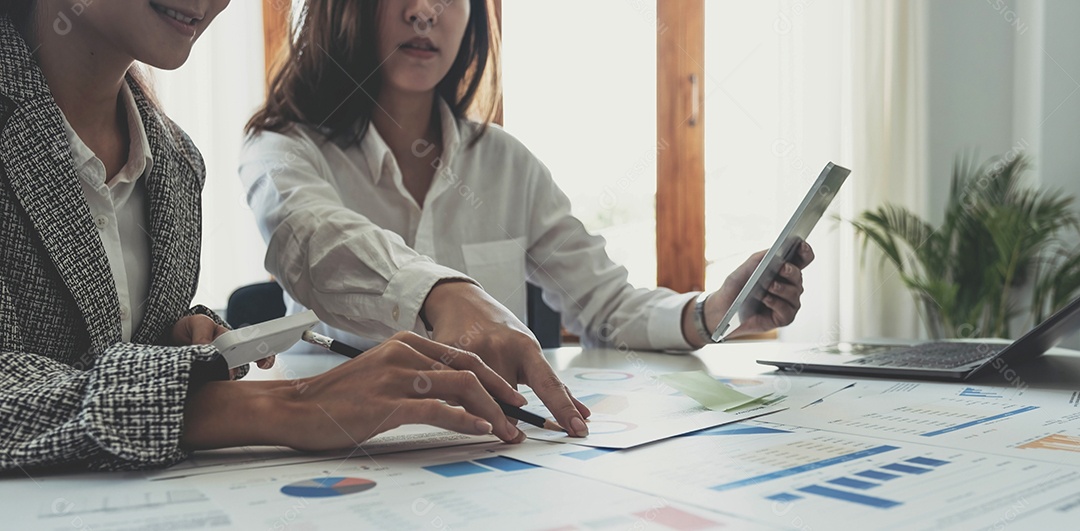 Duas jovens empresárias asiáticas discutem o trabalho do projeto de investimento e a estratégia de planejamento.