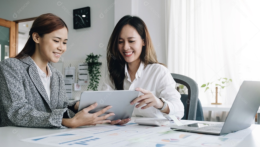 Duas belas jovens empresárias asiáticas trabalhando juntas usando tablet digital no escritório.