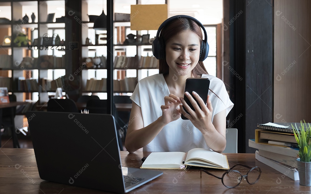 Bela estudante universitária asiática  ouvindo música com seus fones de ouvido sem fio