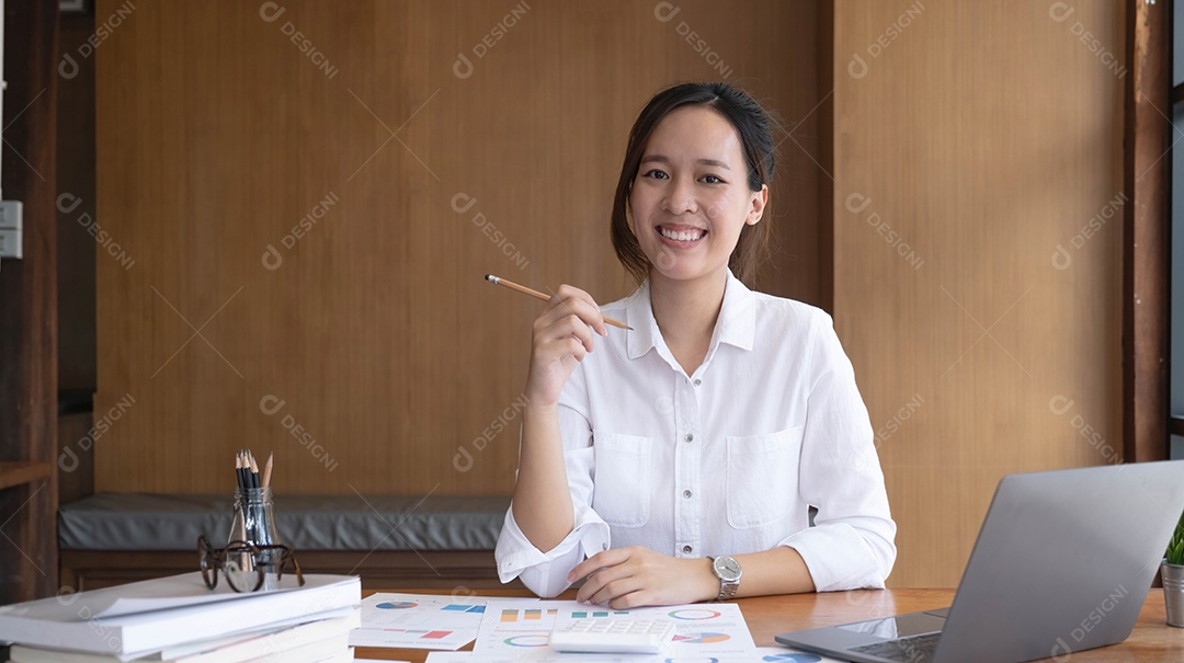 Encantadora mulher asiática trabalhando no escritório usando um laptop