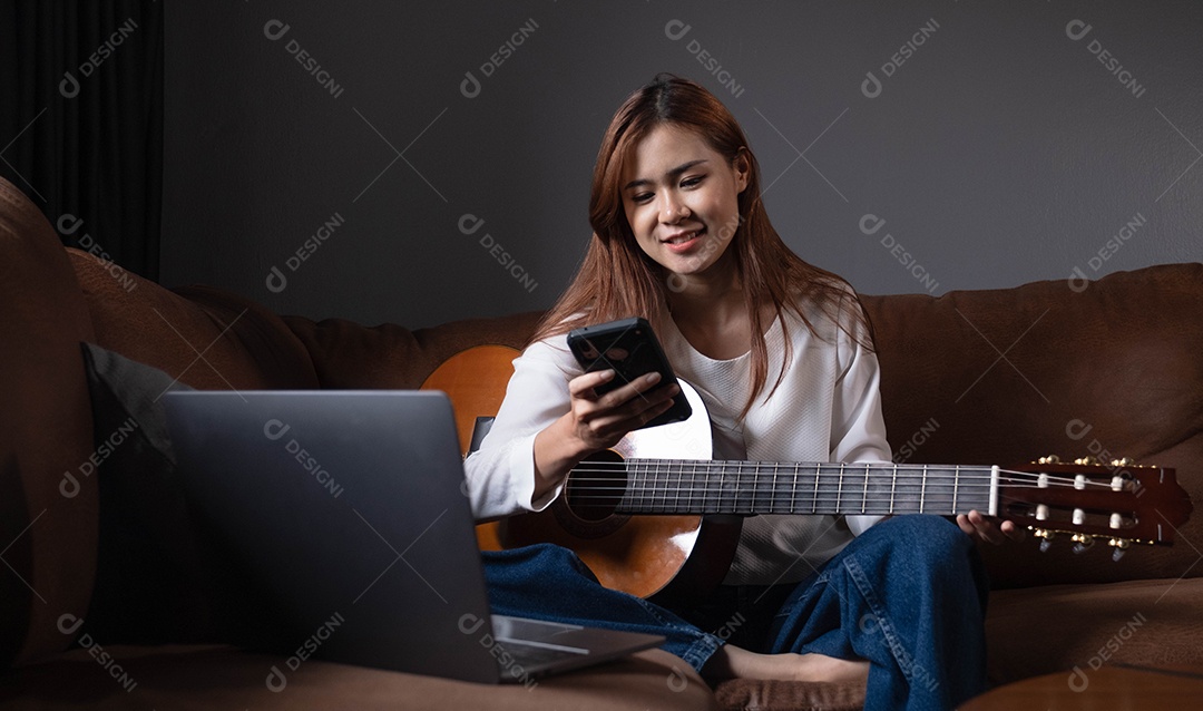 Jovem sentada com violão usando celular