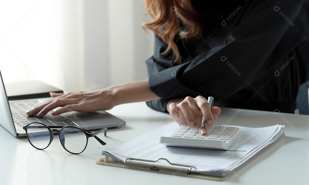 Empresária usando calculadora e laptop para calcular