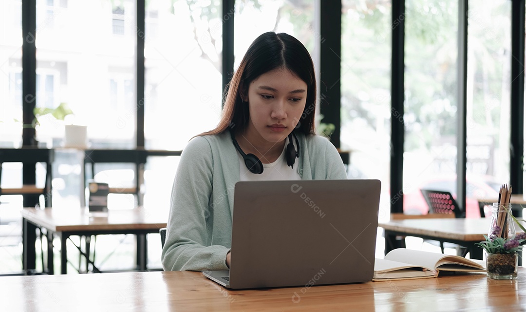 Estudante asiático sério e focado usando laptop olhando para a tela com atenção e concentração