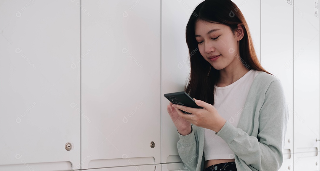 Jovem asiática usando celular e sorrindo