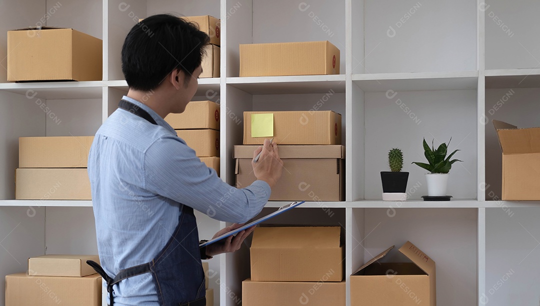 O jovem asiático vendedor prepara a caixa de entrega para o cliente