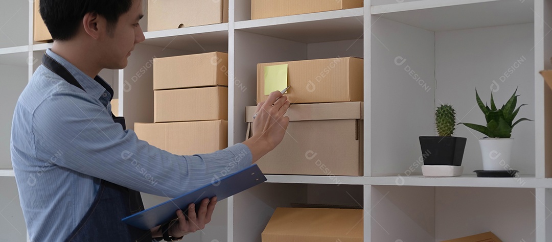 O jovem asiático vendedor prepara a caixa de entrega para o cliente