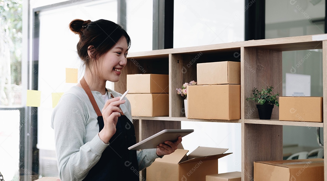 Jovem linda e feliz empresária asiática proprietária de PME on-line usando laptop recebe pedido do cliente