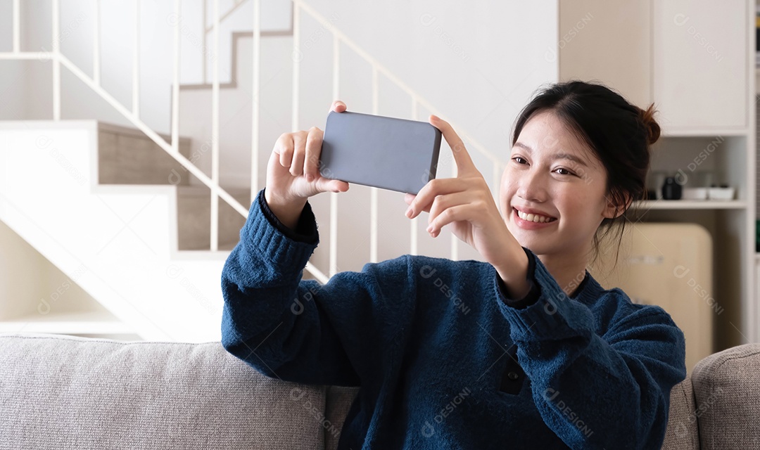 Foto de uma jovem asiática feliz tirando selfie com seu celular