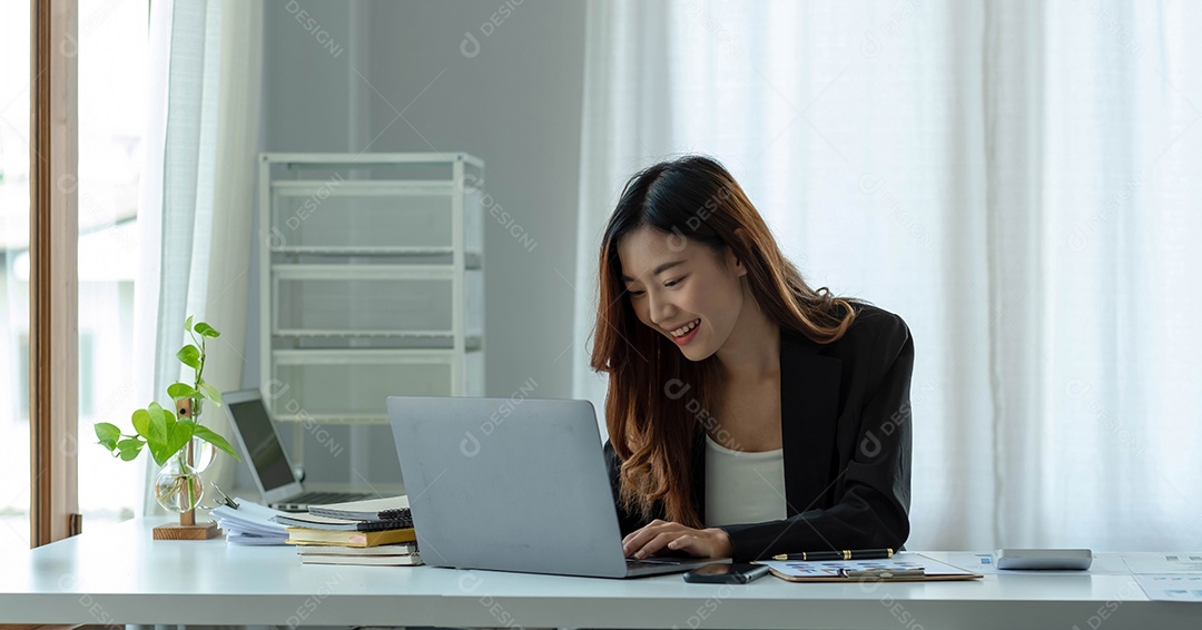 Encantadora empresária asiática sentada trabalhando no laptop no escritório