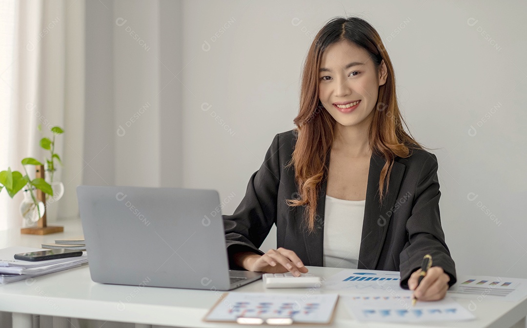 Encantadora mulher asiática trabalhando no escritório usando um laptop