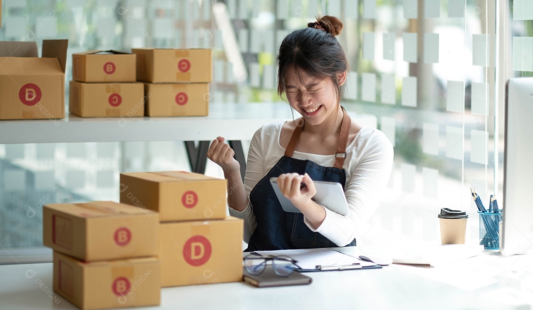 Proprietário de uma pequena empresa usando um avental está vendendo com sucesso on-line