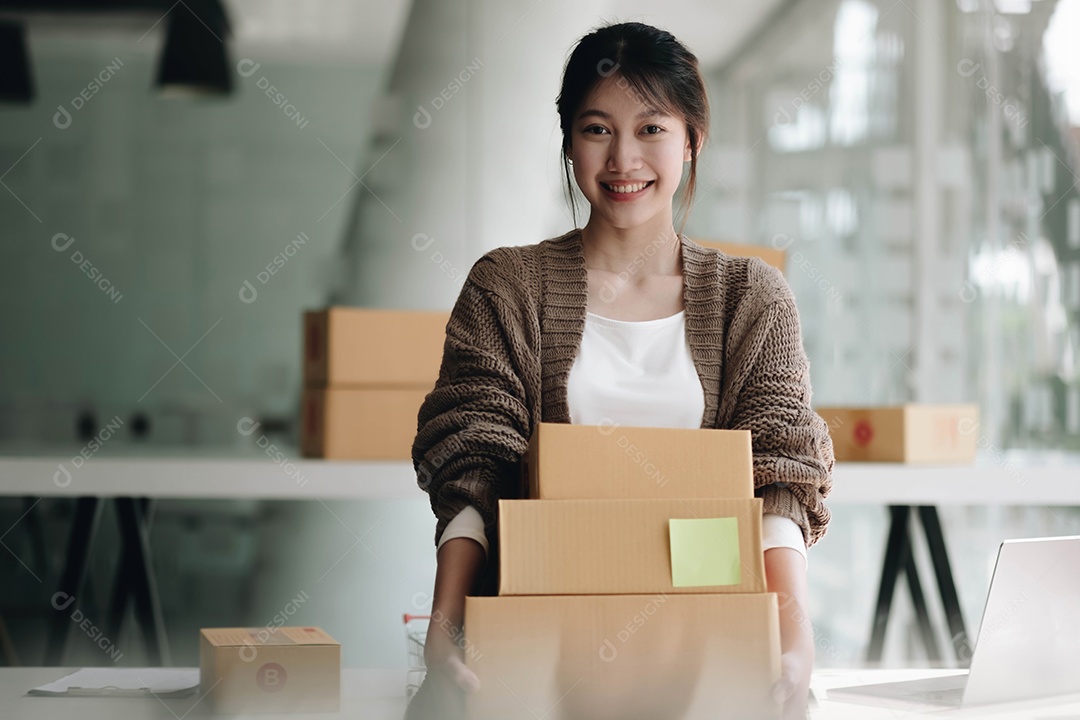 Feliz jovem asiática iniciando pequenas empresas freelancer segurando caixa de encomendas