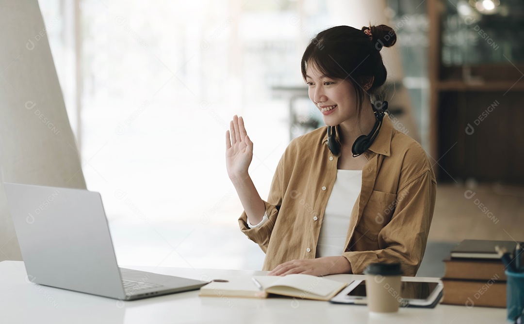 Mulher asiática usando fones de ouvido no pescoço usando laptop
