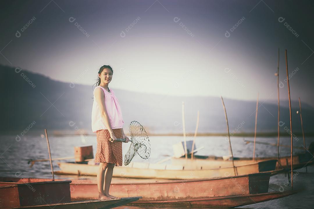 Pescador de mulheres asiáticas está dirigindo um barco para pegar peixes