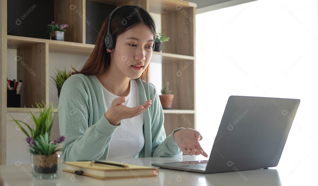 Mulher jovem feliz estudante em fones de ouvido falando olhando para laptop