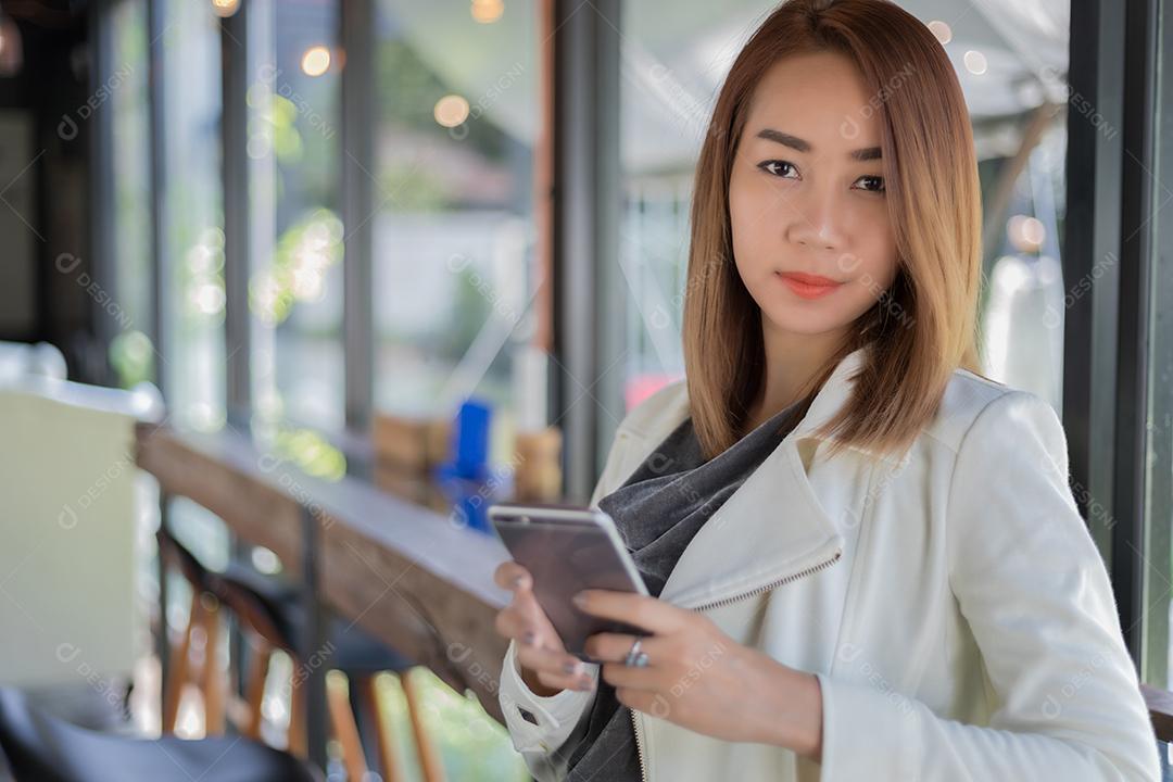 mulher asiática usando telefone para fazer compras on-line e ligar com telefone celular no café durante o tempo livre