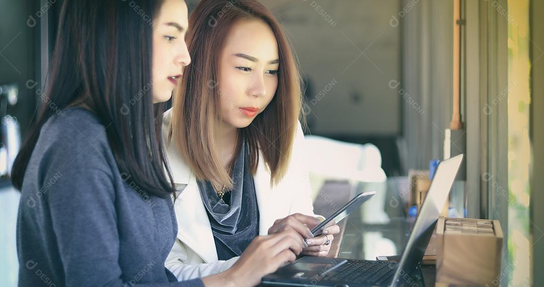Duas mulheres de negócios asiáticas usando notebook trabalhando e discussão do importante contrato no escritório