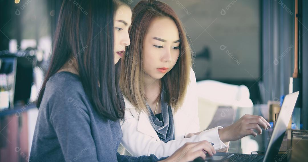 Duas mulheres de negócios asiáticas usando notebook trabalhando e discussão do importante contrato no escritório