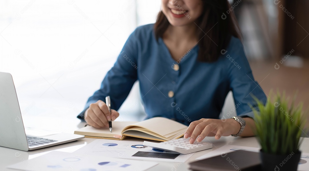 Alegre mulher jovem com laptop, escrevendo no caderno