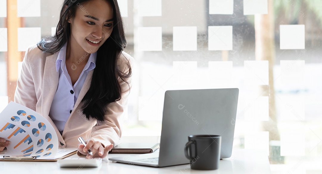 Encantadora empresária asiática sentada trabalhando no laptop no escritório