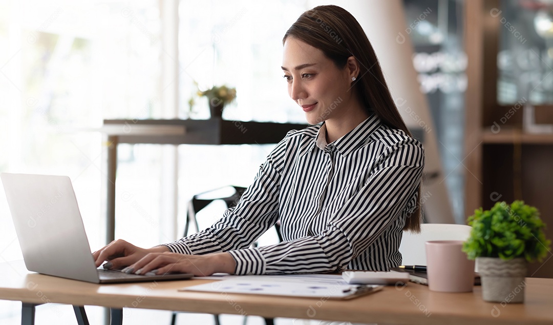 Encantadora mulher asiática trabalhando no escritório usando um laptop