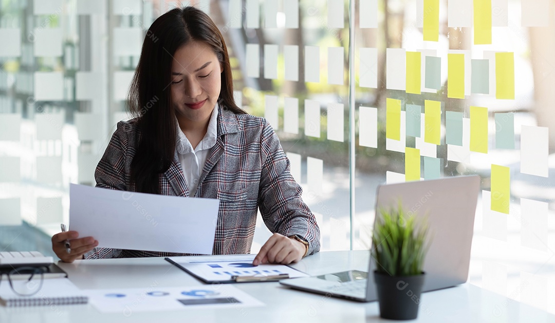 Mulher de negócios asiática sorridente sentada em um escritório moderno.
