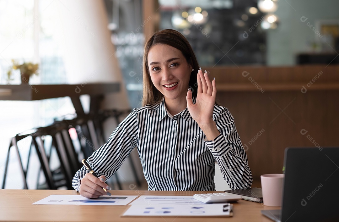 Feliz jovem empresária asiática sentada em seu local de trabalho