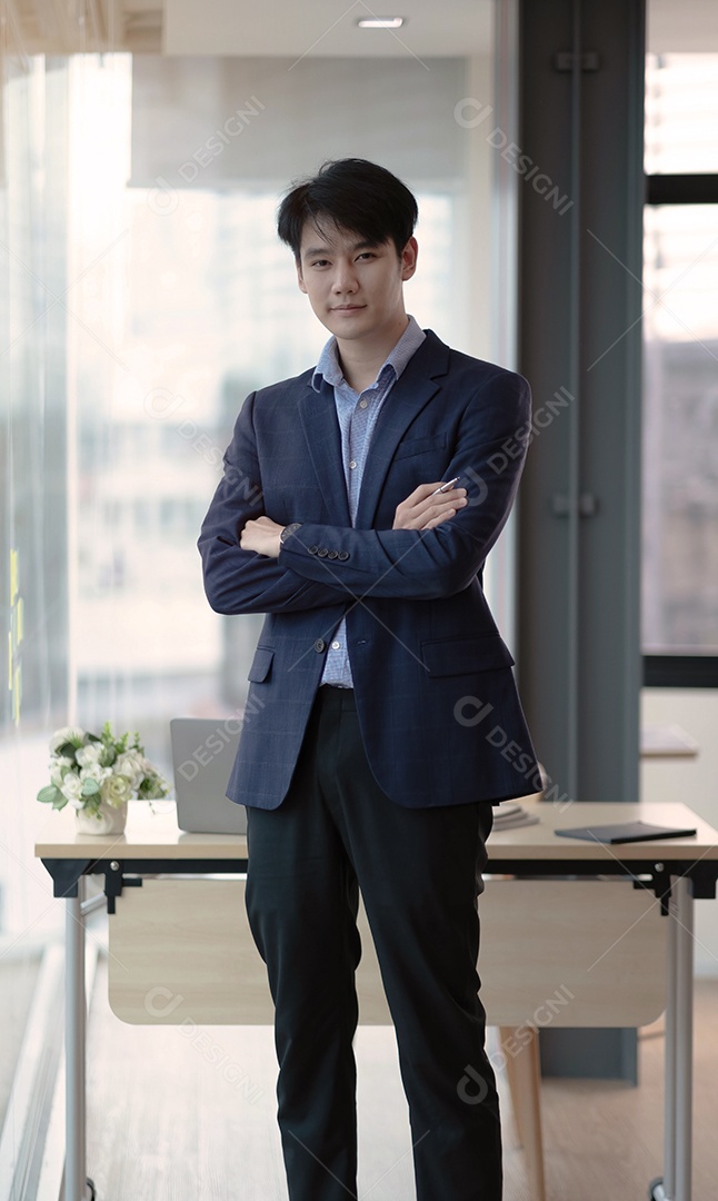 Jovem empresário de pé no escritório olhando para a câmera