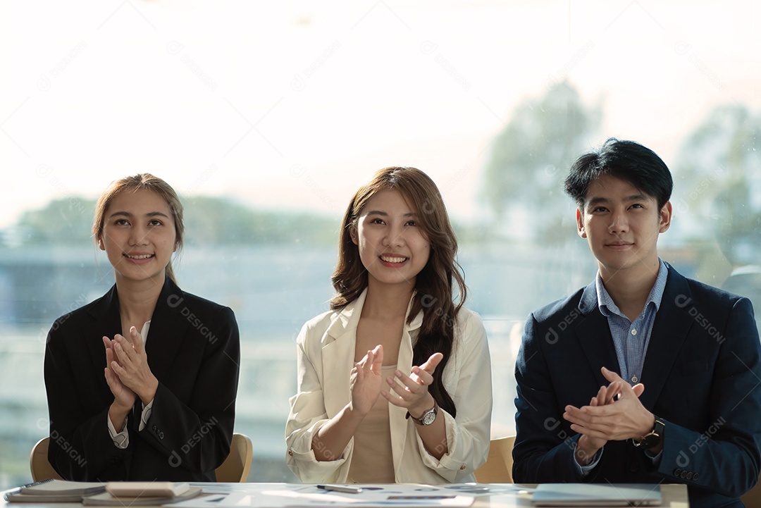 grupo asiático de jovens alegres sentados em uma reunião com aplausos.