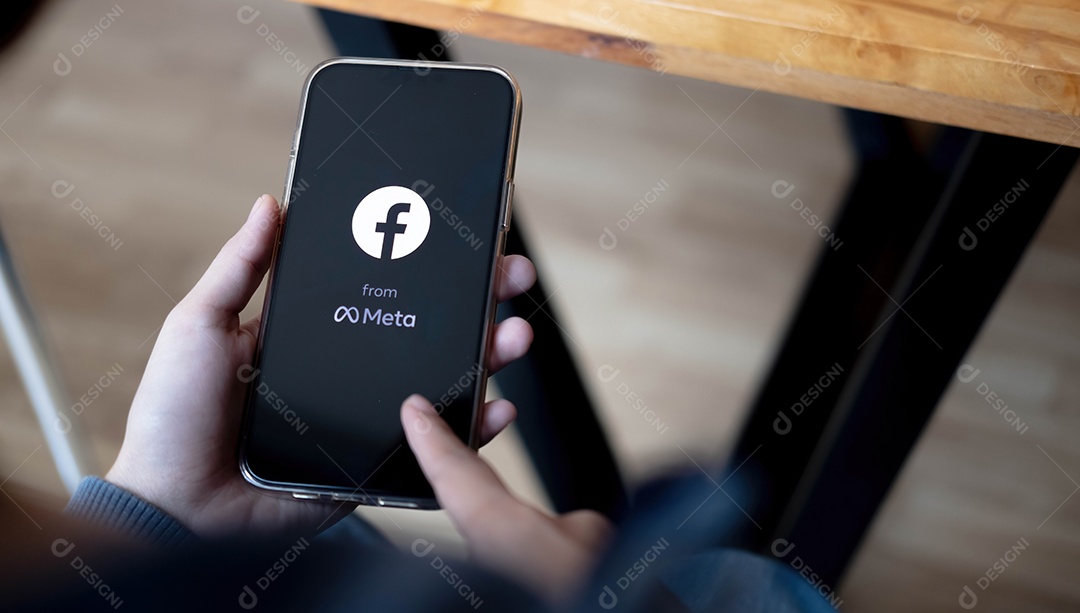 Mulher segurando um iPhone Pro Max com serviço social de Internet Facebook na tela.