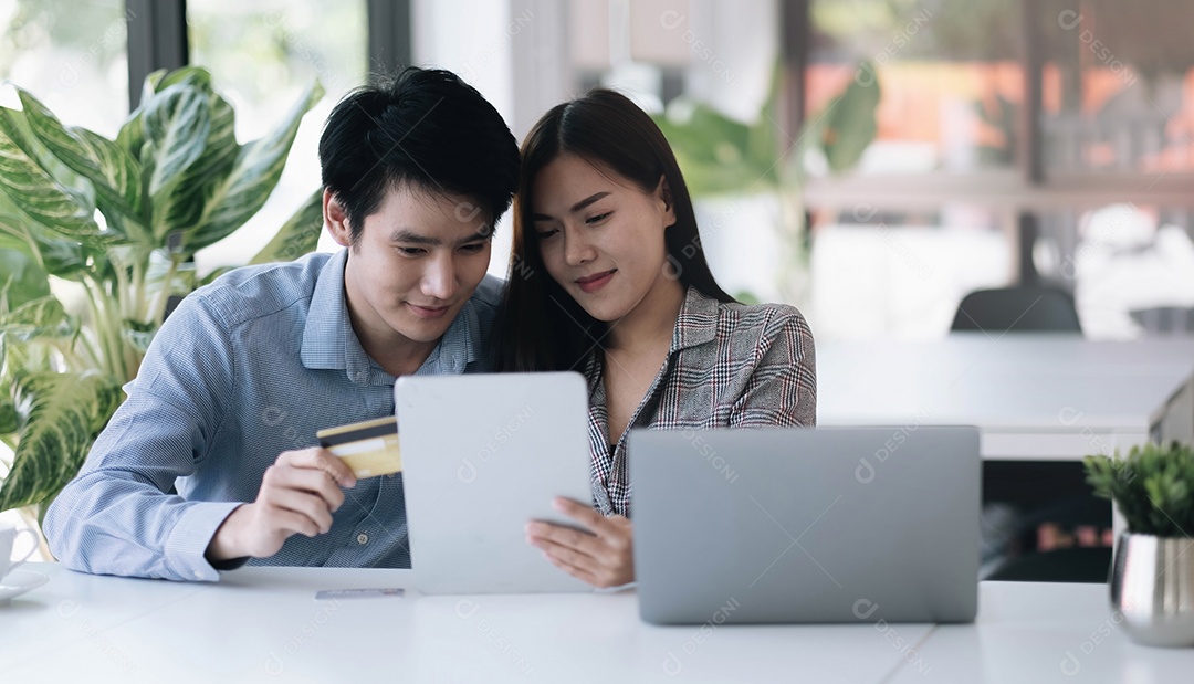 Jovem casal segurando o cartão de crédito e usando o telefone. Compras online