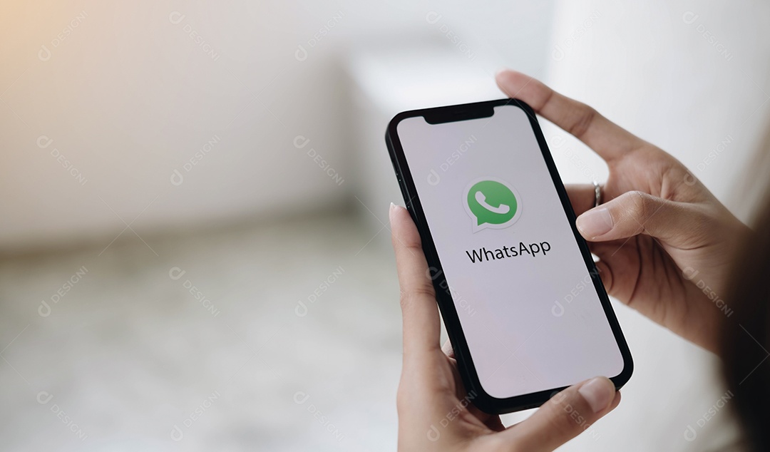 Homem segurando um iPhone com serviço social de Internet WhatsApp na tela.