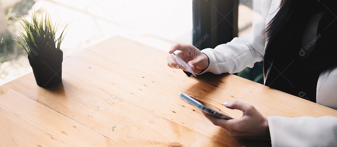 Pagamento online, mãos femininas segurando um cartão de crédito