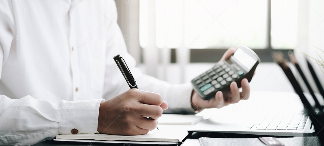 Homem de negócios usando calculadora e laptop para fazer matemática