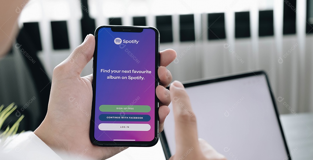 Pessoa segurando um novo Apple iPhone XS com o logotipo do Spotify na tela.