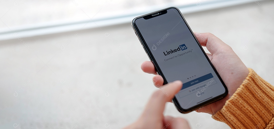 Mulher segura o Apple iPhone Xs com o aplicativo LinkedIn na tela.