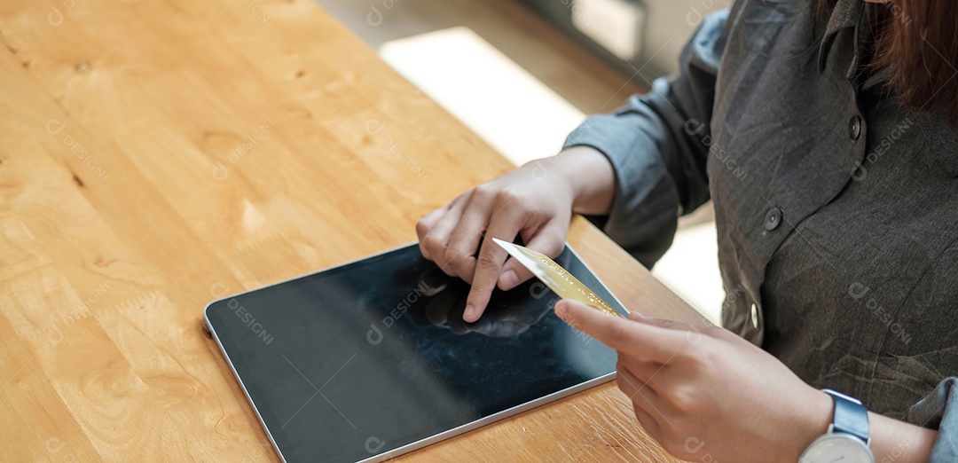 Mão de uma mulher segurando o cartão de crédito usando laptop para loja online