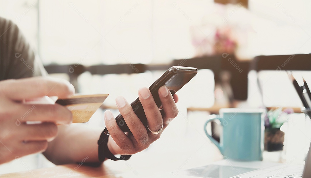 Pagamento online, as mãos do homem segurando o smartphone e usando o cartão de crédito