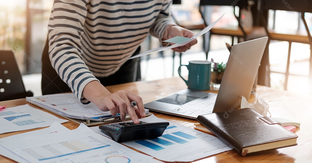 Mão de uma mulher ou contador segurando uma caneta trabalhando em calculadora
