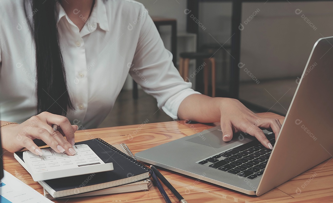 Empresária usando calculadora e laptop para cálculos