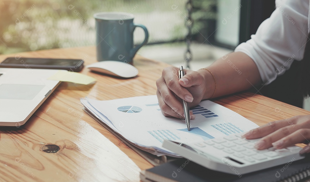 Mão da empresária segurando a caneta e apontando para finanças