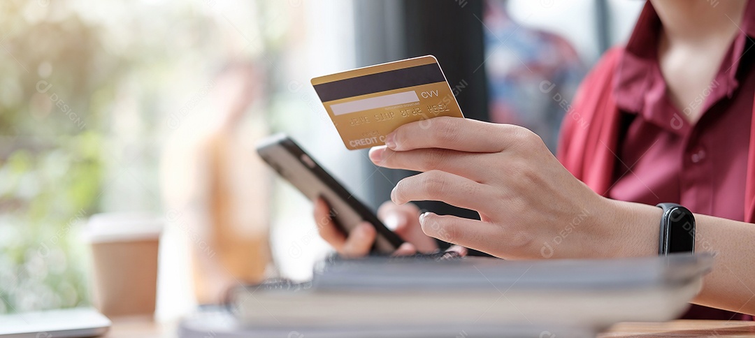 Mãos de mulher fazendo pagamento online segurando smartphone e usando cartão de crédito