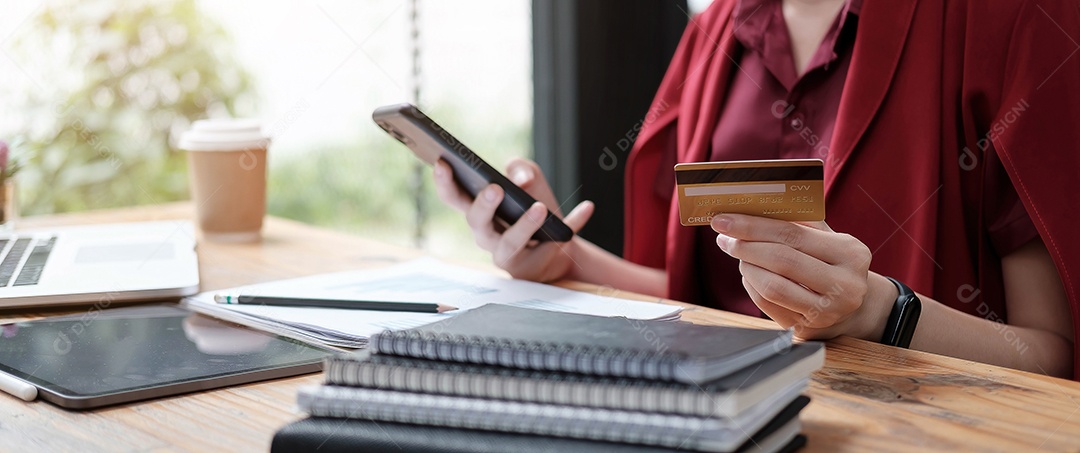 Mãos de mulher fazendo pagamento online segurando smartphone e usando cartão de crédito