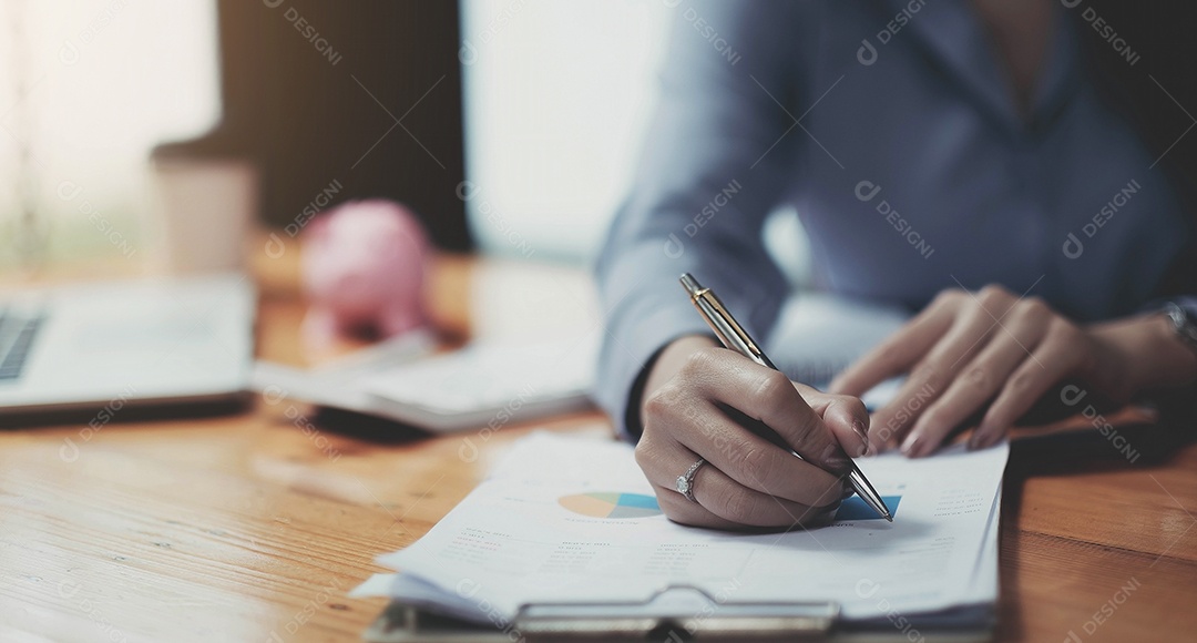 Mão da empresária segurando a caneta e apontando para finanças