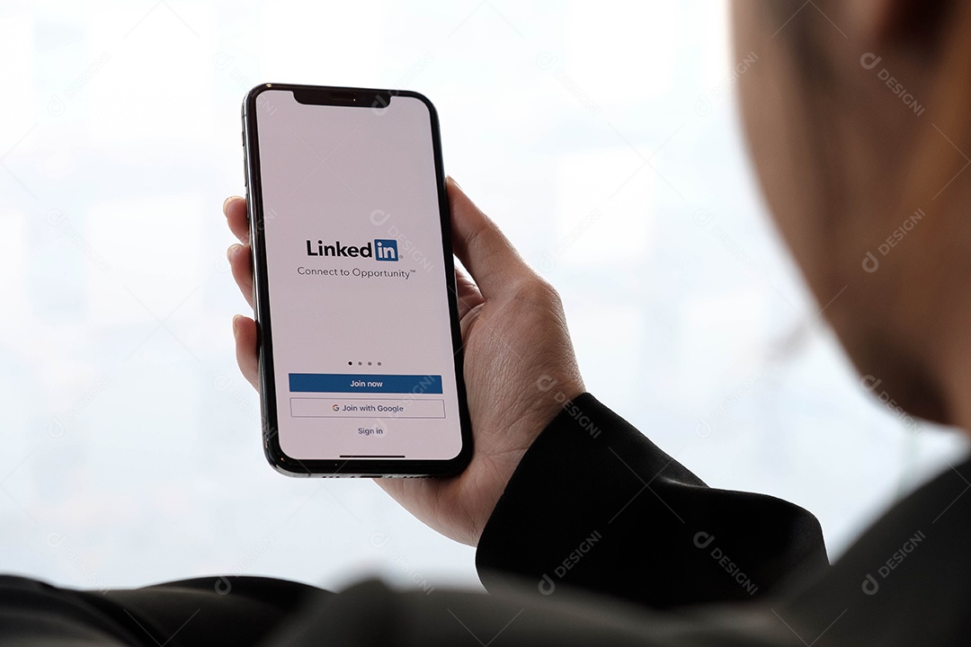 Uma mulher segura o Apple iPhone X com o aplicativo LinkedIn na tela.