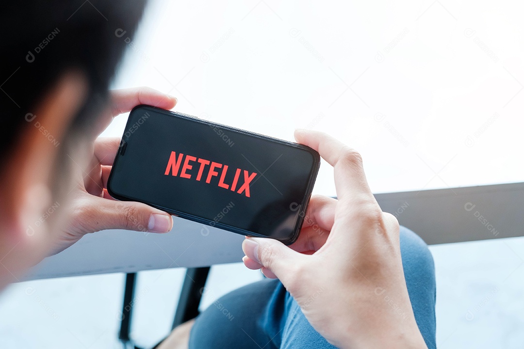 Mão de homem segurando o telefone inteligente com o logotipo da Netflix no Apple iPhone Xs.