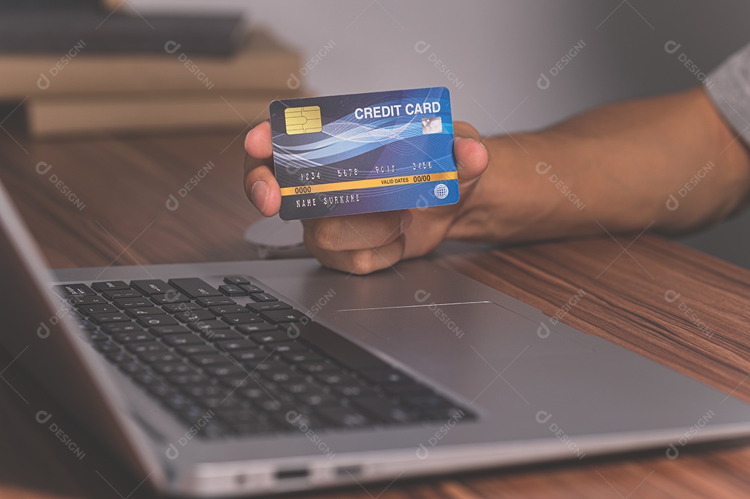 Pessoa usando cartões de crédito para fazer compras online por meio de notebooks.