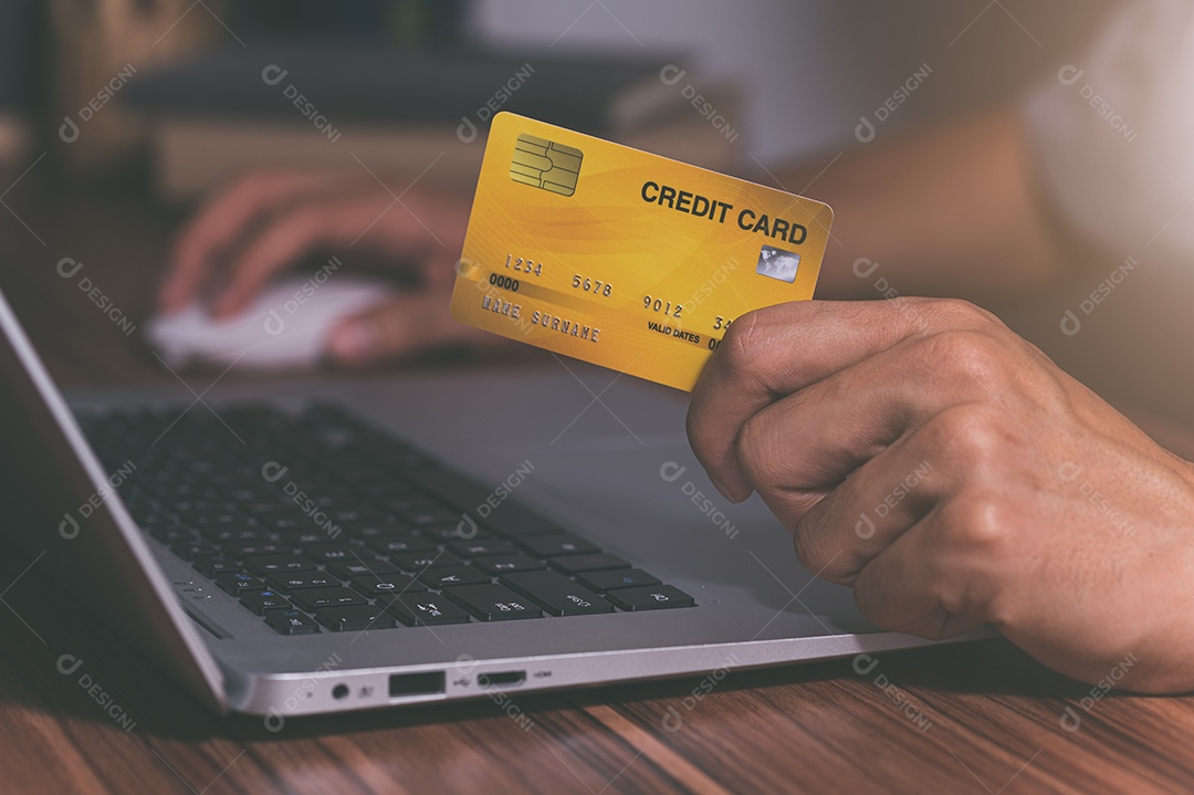 Pessoa usando cartões de crédito para fazer compras online por meio de notebooks.