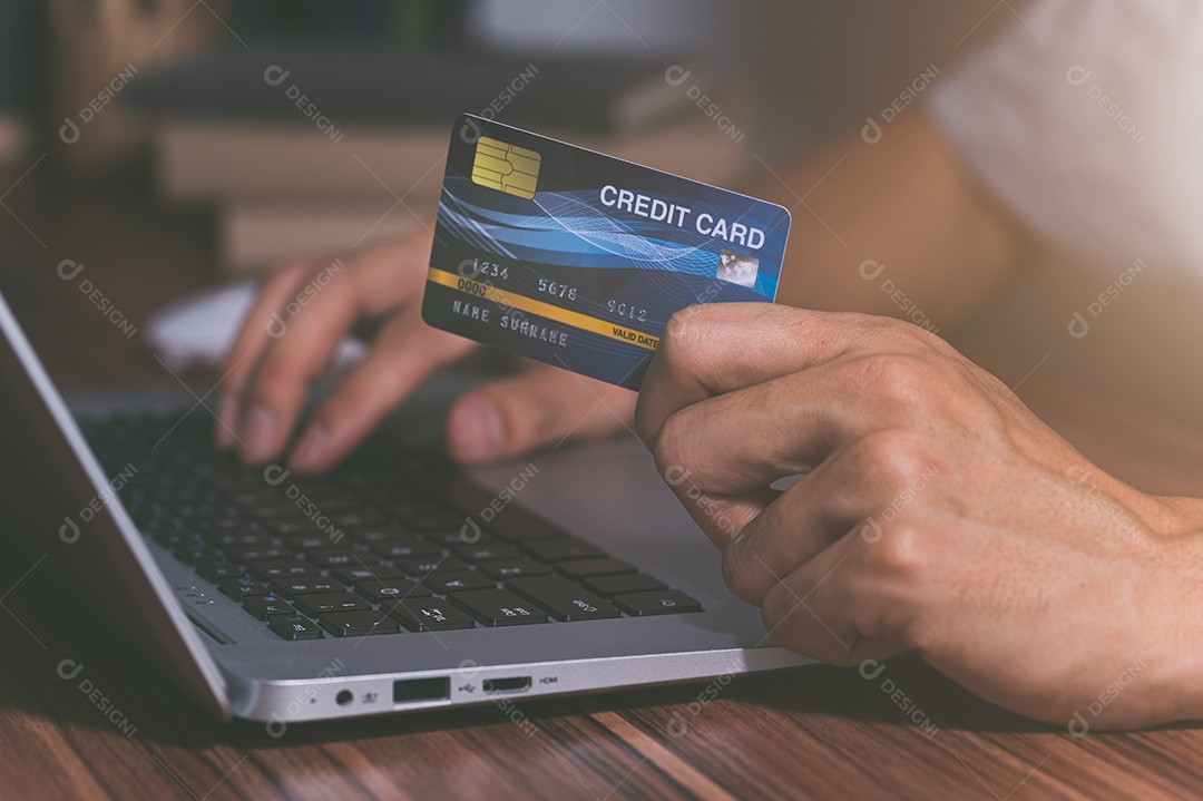 Pessoa usando cartões de crédito para fazer compras online por meio de notebooks.