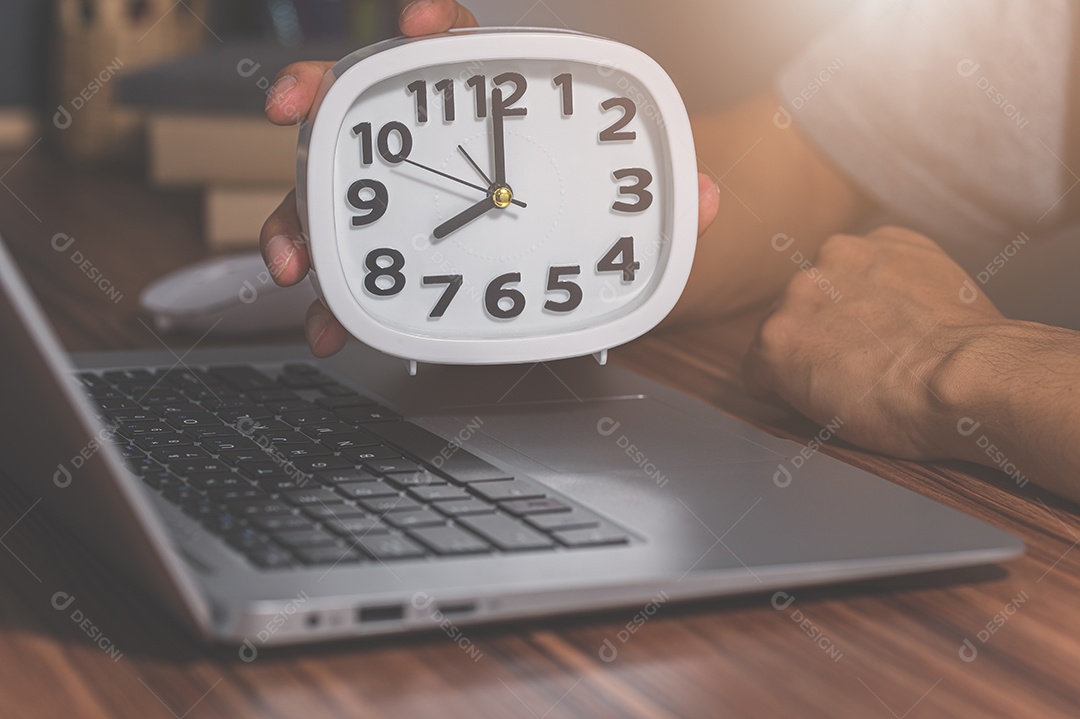 Segurando um relógio de mesa na mesa de trabalho